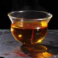 Würzen mit Safranfäden im warmen Teeglas Würzen mit Safranfäden im warmen Teeglas
